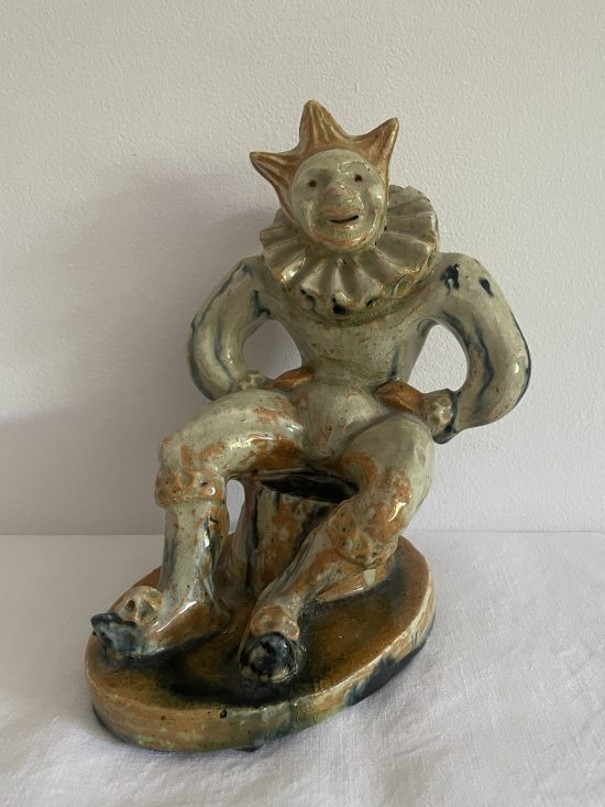 Ceramic figure of a seated, grinning jester or clown